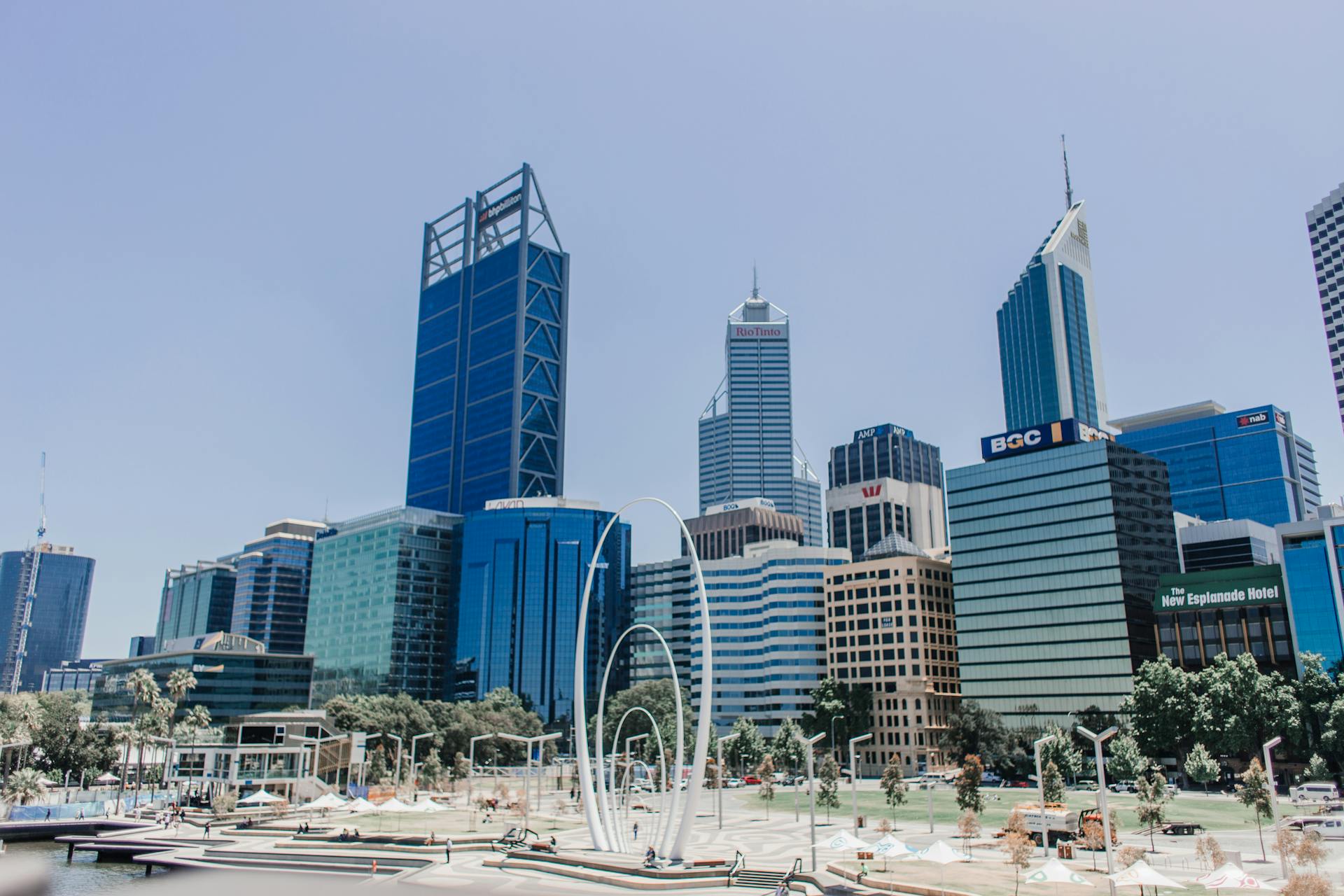View of tall skyscrapers in Perth seen through the white, rippled arches of the "Spanda" sculpture at Elizabeth Quay