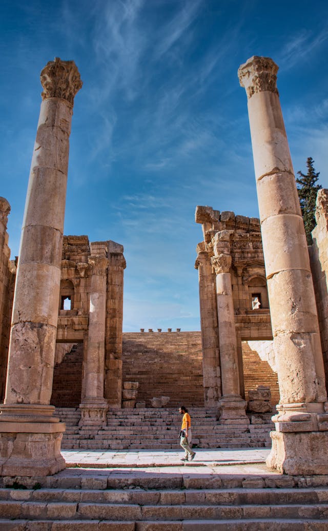 Tall ancient stone columns from a Roman temple ruin standing against a bright blue sky.